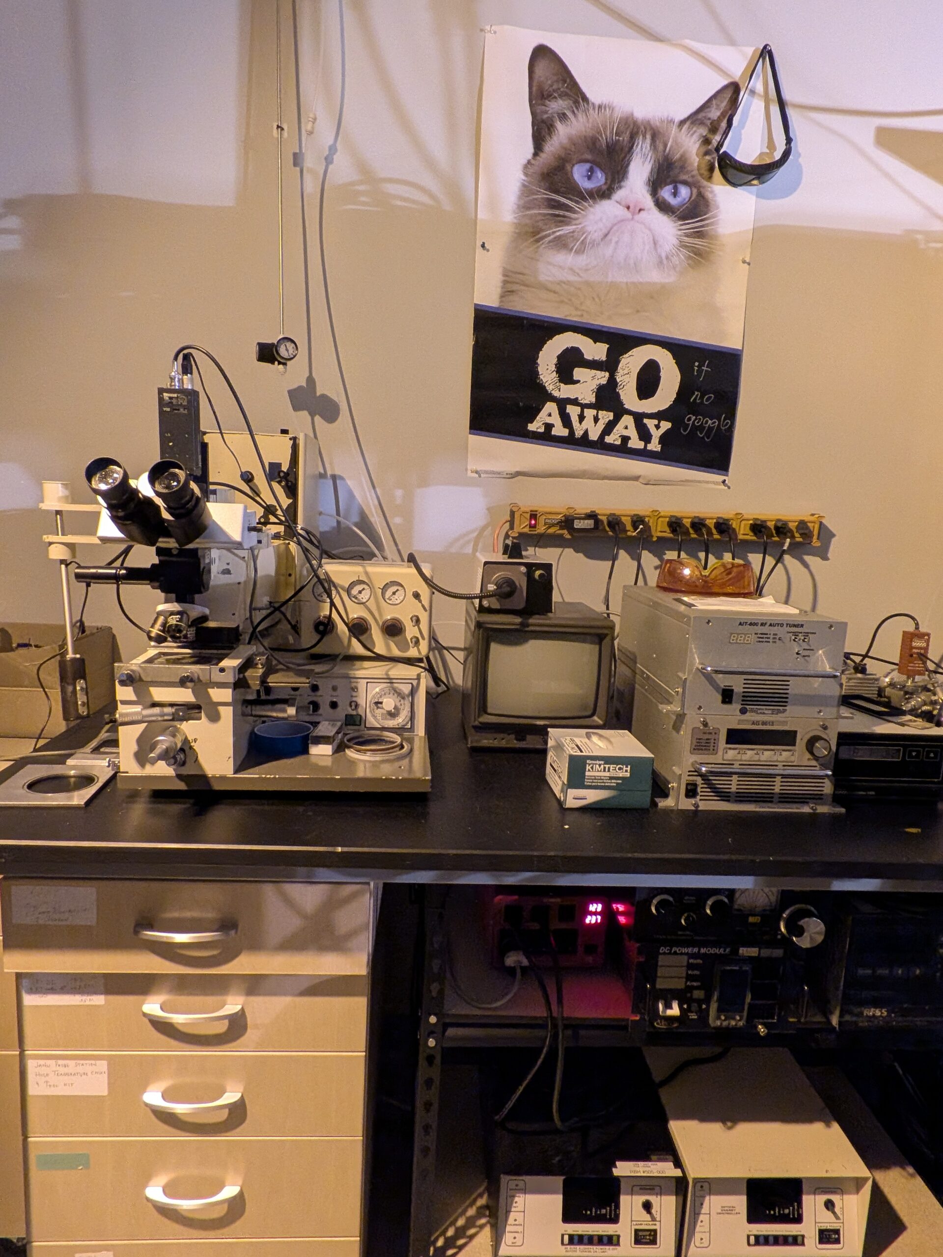 Characterization bench with microscope, RF equipment, and safety signage